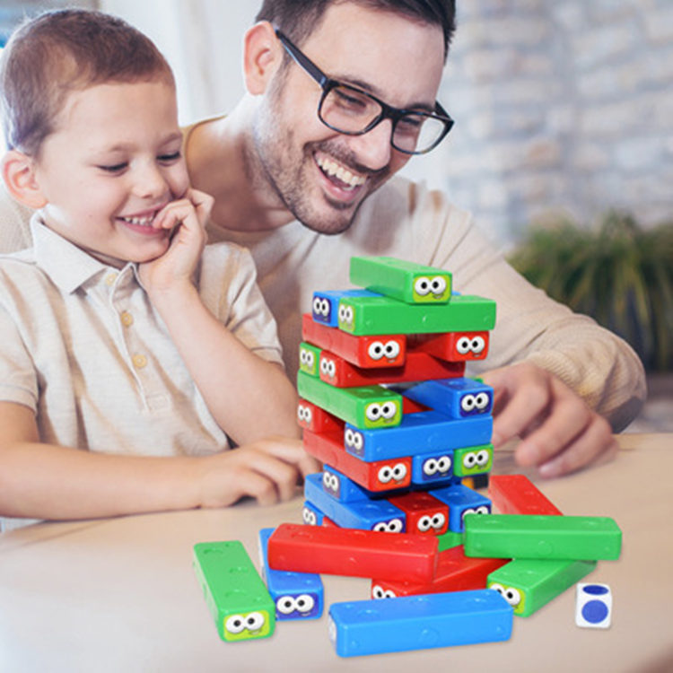 Man and child playing with colorful building blocks on a table.