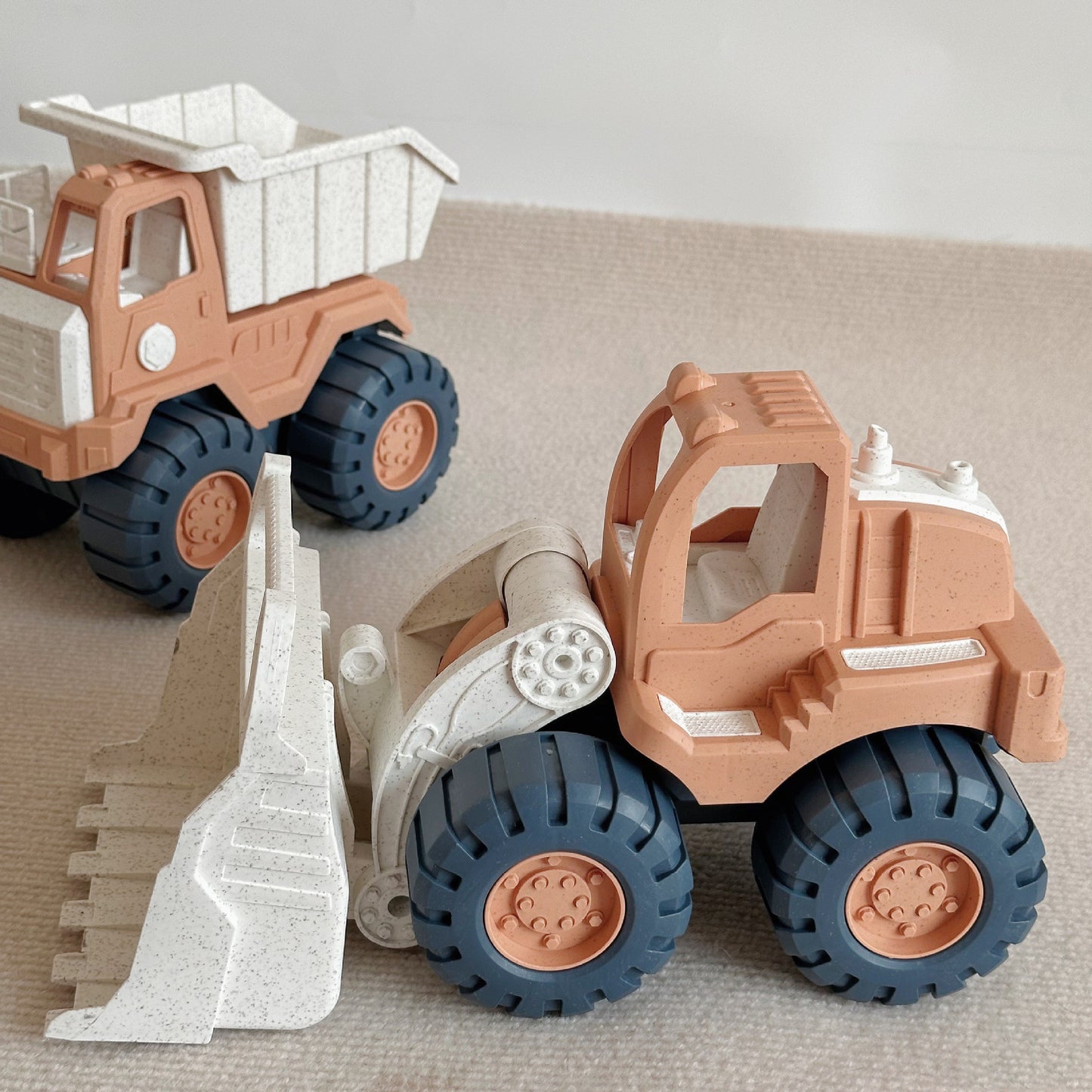 Two toy construction vehicles, a dump truck and a bulldozer, on a neutral background.