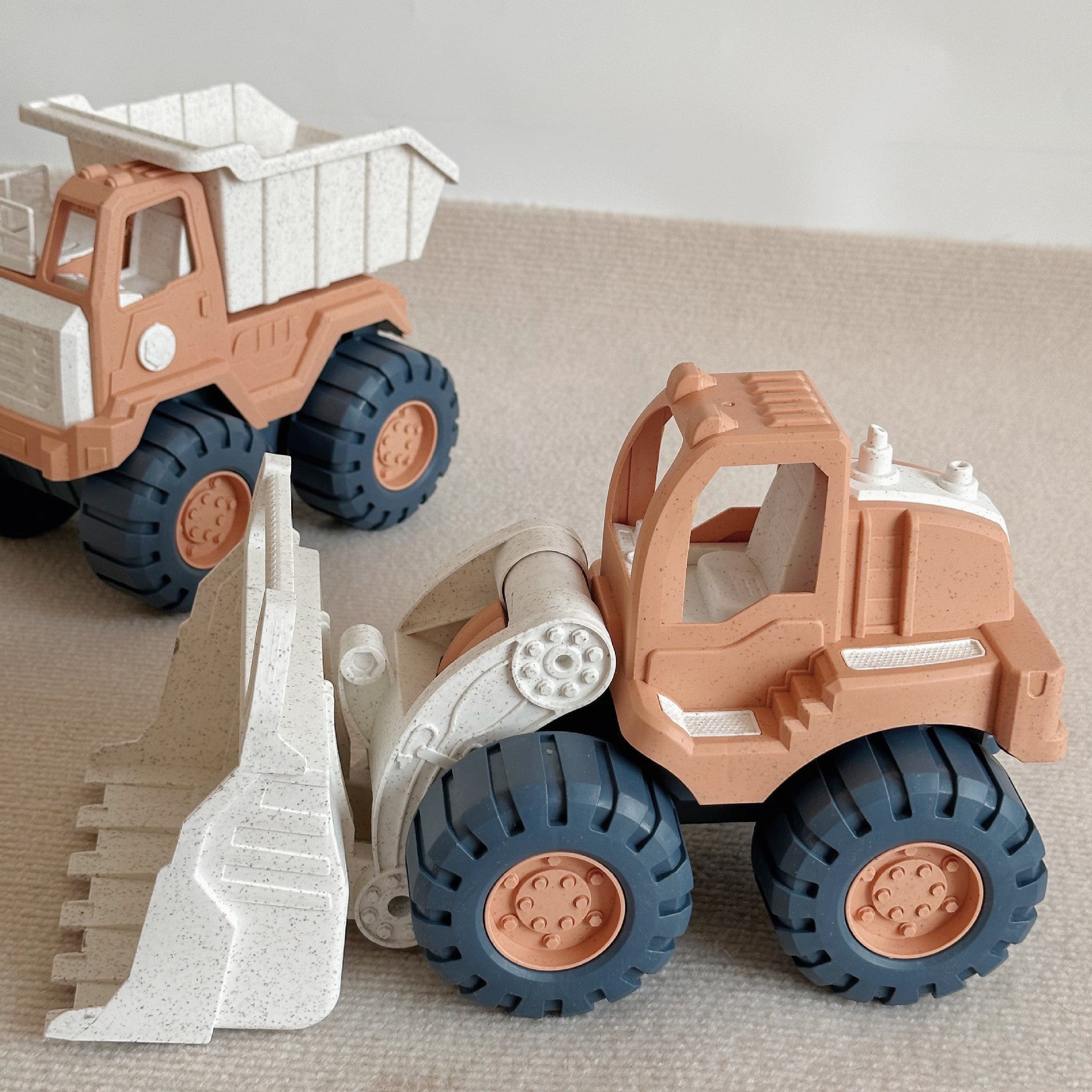 Two toy construction vehicles, a dump truck and a bulldozer, on a neutral background.