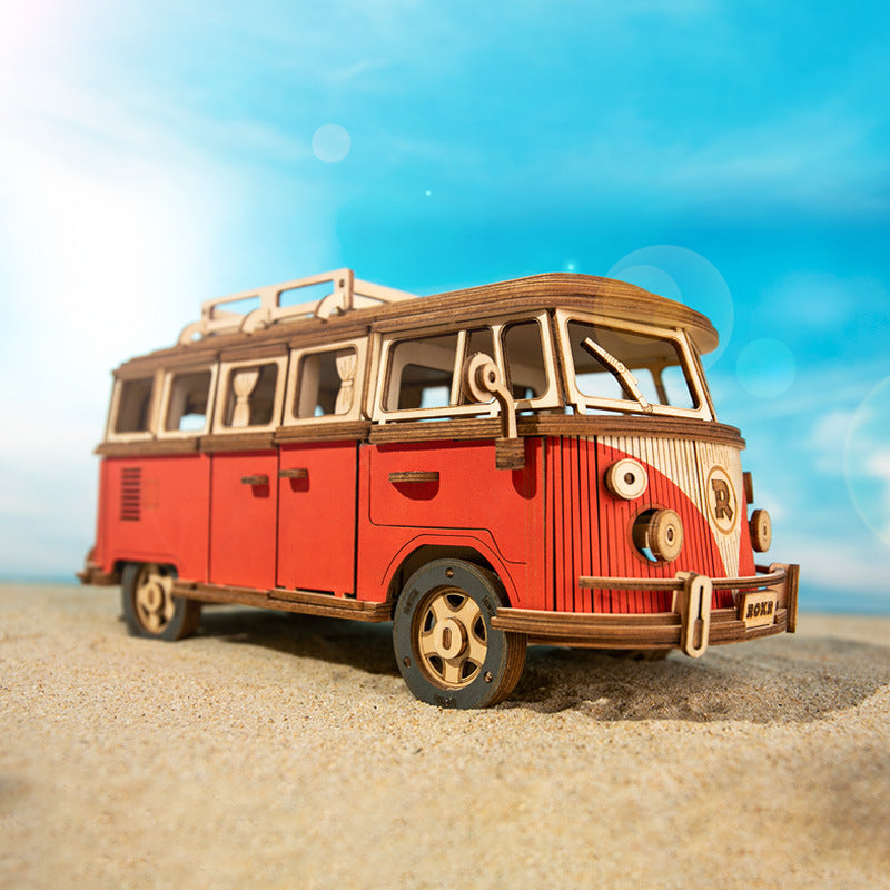 Model of a red and brown vintage van on a sandy beach with a blue sky.