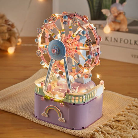 Decorative model of a Ferris wheel with lights on a wooden surface.