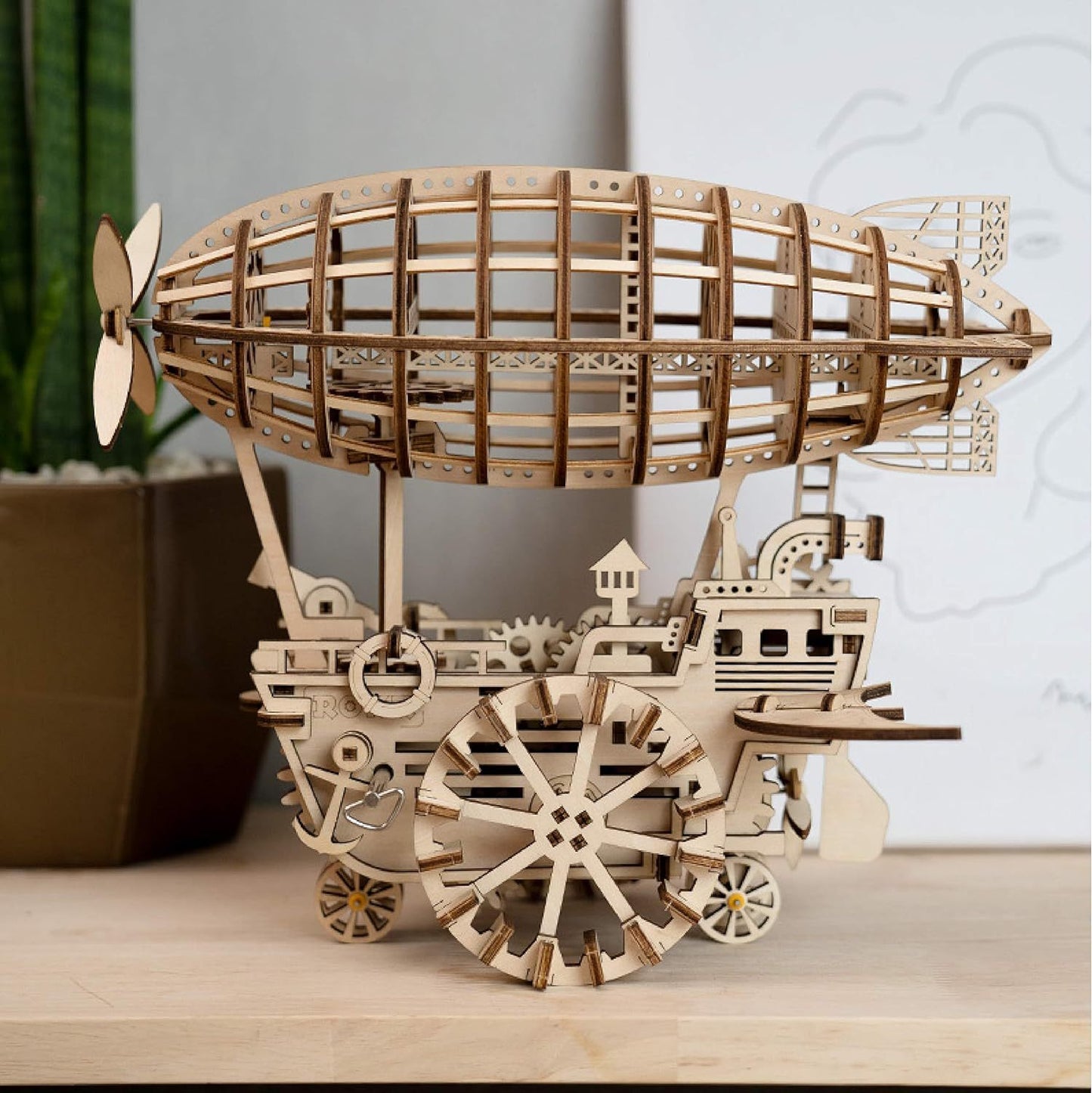 Wooden model of a steampunk airship on a wooden surface with a neutral background